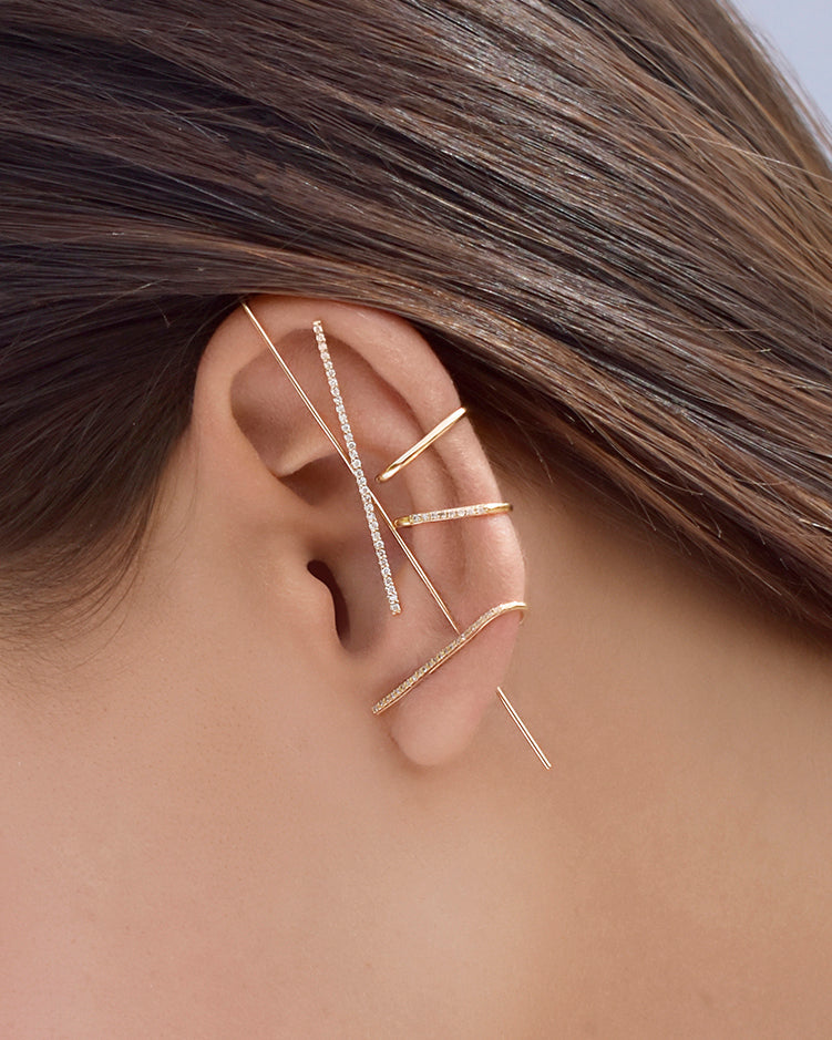 Close-up of an ear wearing gold earrings with a neutral background