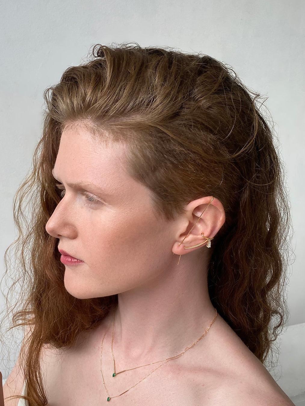Woman with styled hair and jewelry against a plain background