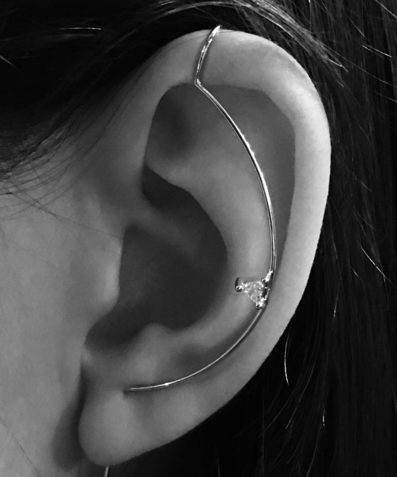 Close-up of an ear wearing a white gold earring with a triangle diamond.